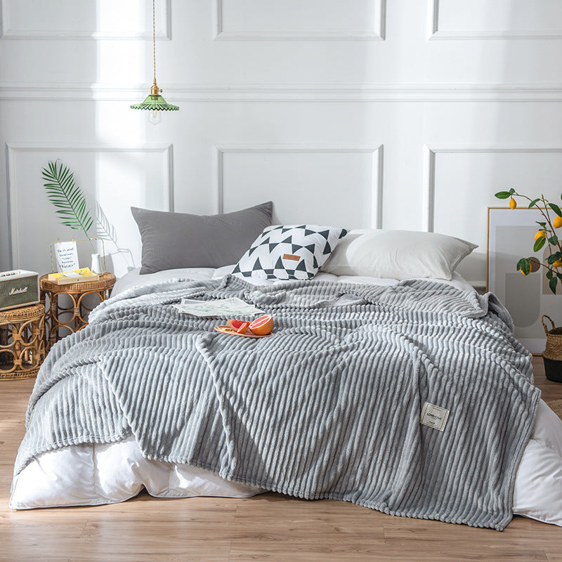 Plaid en flanelle grise côtelée disposé sur un lit