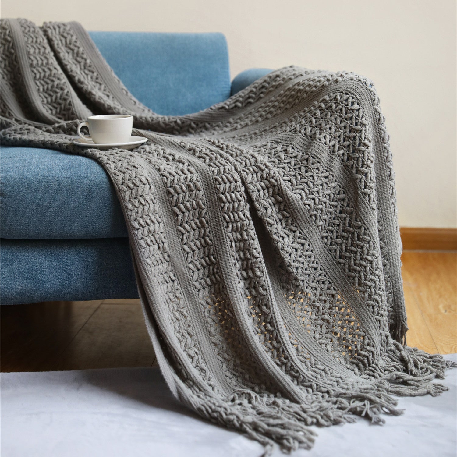 Plaid nordique tricoté gris fumé avec franges sur un canapé