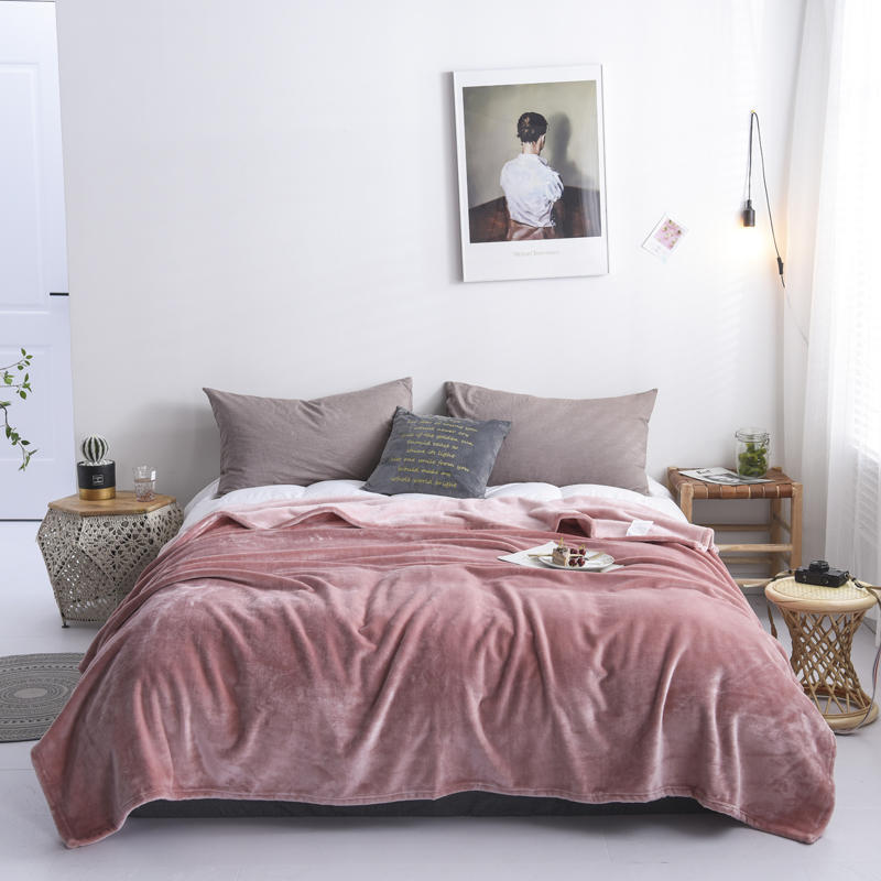 Plaid en flanelle rose poudré disposé sur un lit