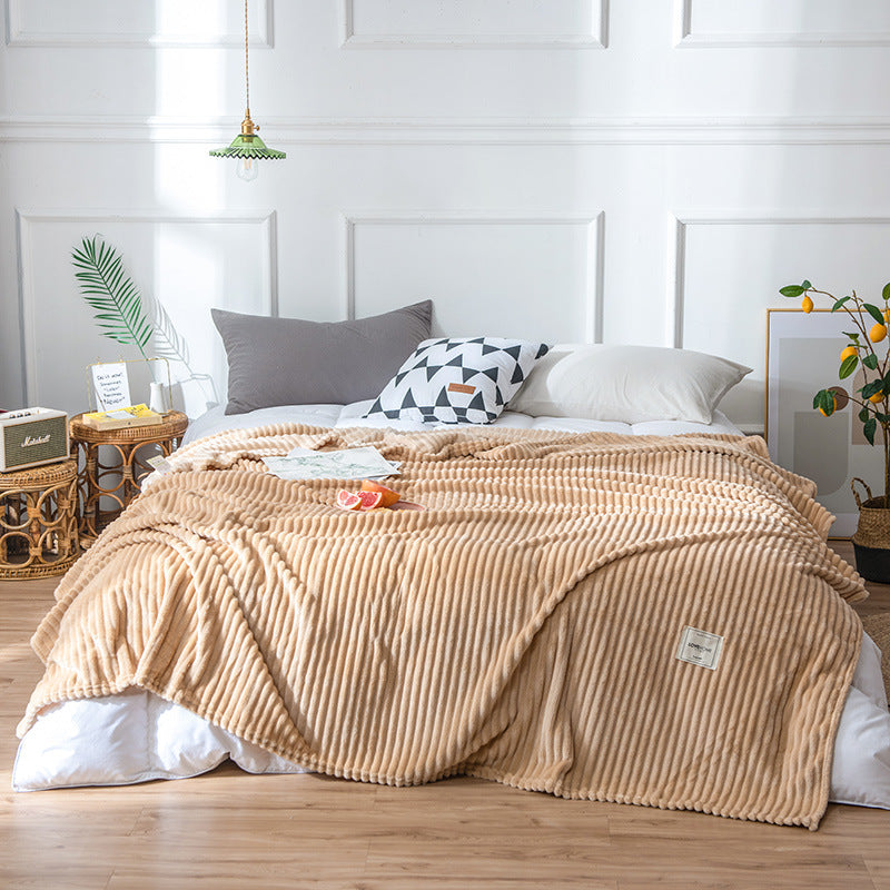 Plaid en flanelle beige côtelée disposé sur un lit