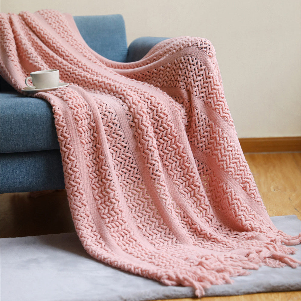 Plaid nordique tricoté rose avec franges sur un canapé bleu